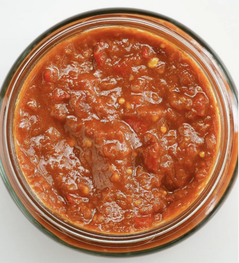 Jar of red relish sauce on a white background