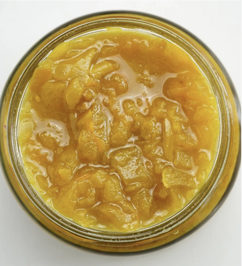 Jar of yellow preserve on a white background