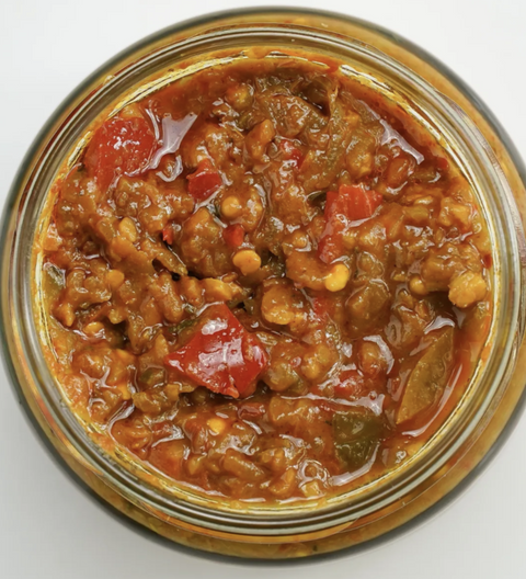 Jar of chili with visible ingredients on a white background