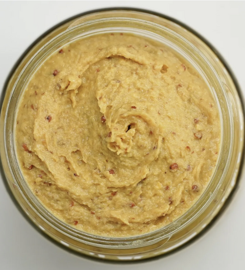 Jar of yellow spreadable food on a white background