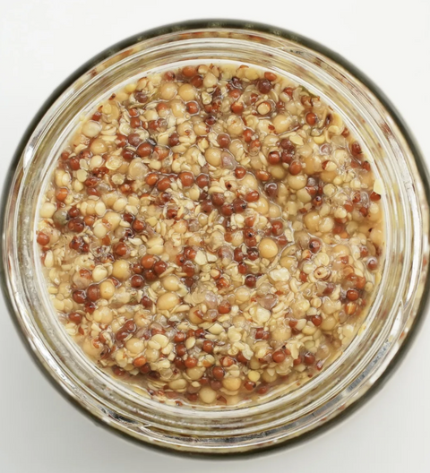 Jar of mustard seeds on a white background