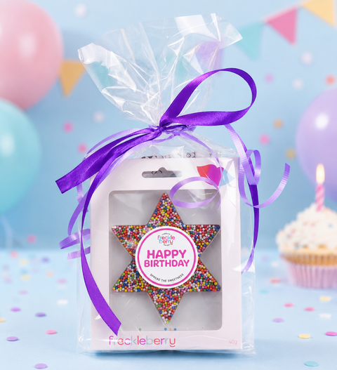 Star-shaped gift with colorful sprinkles in a clear package with premium chocolate block, and bag of milk coated raspberries