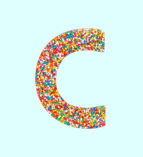 Belgian milk chocolate letter 'C' covered with multicolored sprinkles on a white background.