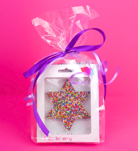 Happy birthday or thank you gift bag Star-shaped decorative item with colorful beads in a clear package with a purple ribbon on a pink background