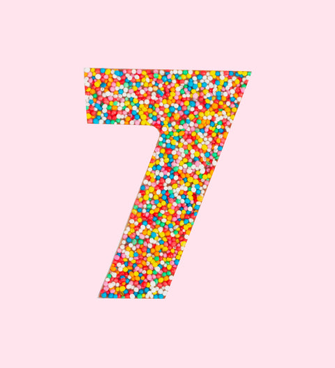Belgian milk chocolate in the shape of the number 7, covered with multicolored sprinkles.