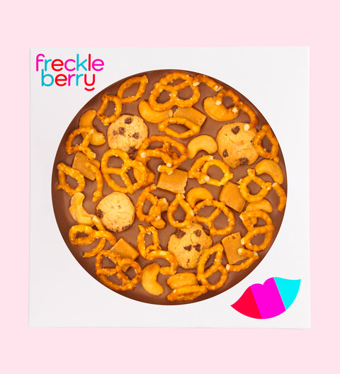 Giant Belgian milk chocolate pizza loaded with pretzels, chocolate chip cookies, caramel fudge, and salted cashews, perfect for sharing, gifting, or enjoying any time.