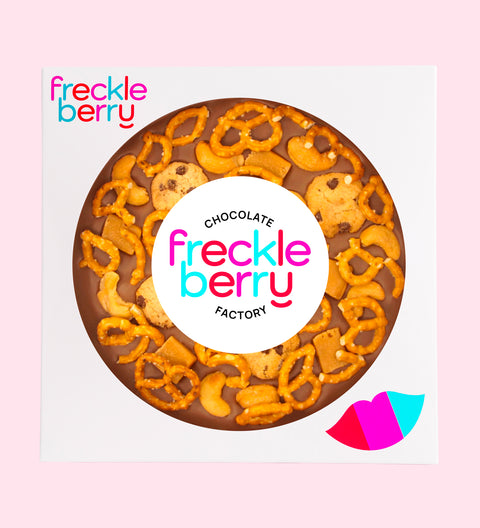 Giant Belgian milk chocolate pizza loaded with pretzels, chocolate chip cookies, caramel fudge, and salted cashews with classic "Freckleberry" label/design - perfect for sharing, gifting, or enjoying any time.