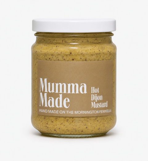 A glass jar of Mumma Made Hot Dijon Mustard with a white lid and a brown paper label, set against a plain white background.
