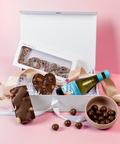 Chocolates, a bottle of wine, and a box with 'LOVE' spelled out in candies in a hamper.
