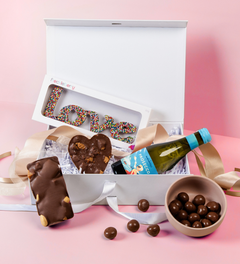 Chocolates, a bottle of wine, and a box with 'LOVE' spelled out in candies in a hamper.