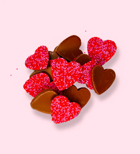 Creamy Belgian milk chocolate freckles shaped like hearts, topped with pink and red freckles. Perfect for gifting or celebrating special moments.