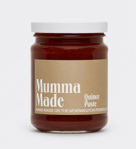 A glass jar of Mumma Made Quince Paste with a white lid and a kraft paper label, set against a plain light gray background.