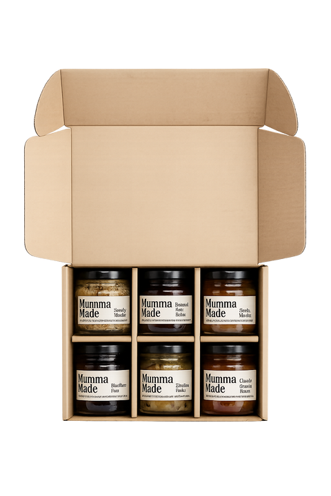 An open kraft cardboard gift box containing six small jars of Mumma Made spreads, arranged in two rows of three on a plain white background.