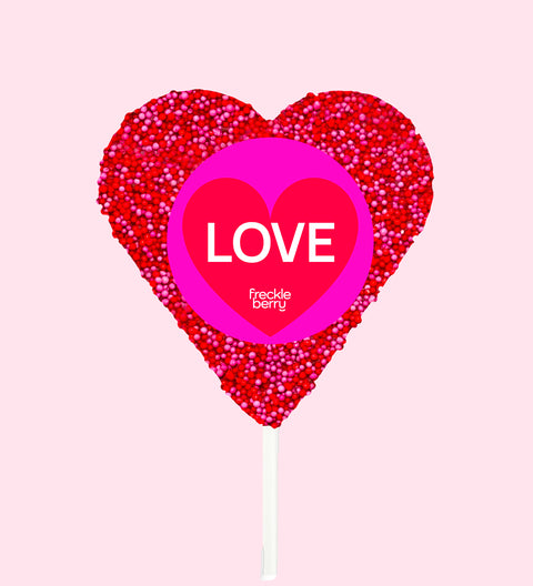 Heart-shaped lollipop with 'LOVE' and brand name on a pink background