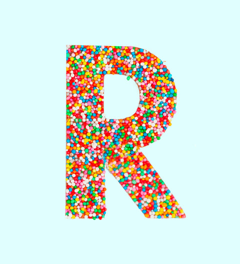 Belgian milk chocolate letter 'R' covered with multicolored sprinkles on a white background