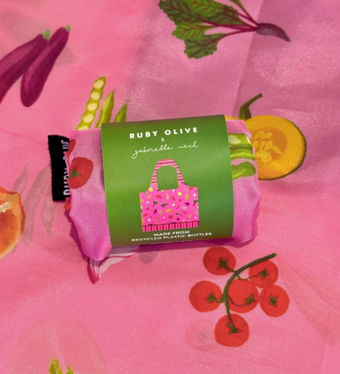 Green packaging with a pink tote bag on a pink background with fruit illustrations