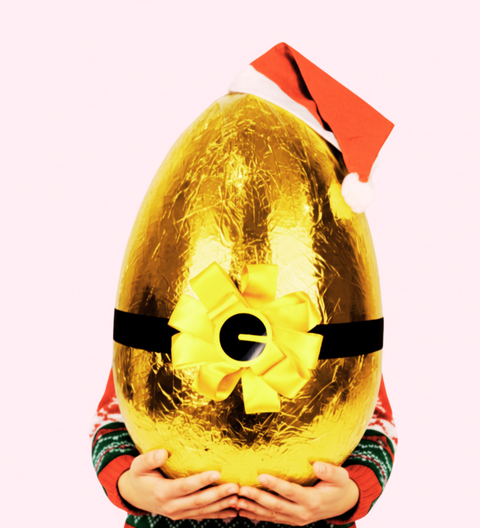 Person holding a large gold Easter egg with a red bow and Santa hat on a white background
