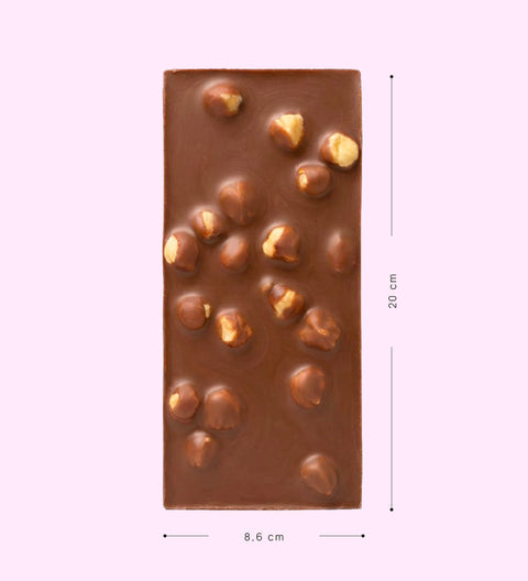 Chocolate bar with nuts on a pink background with measurements