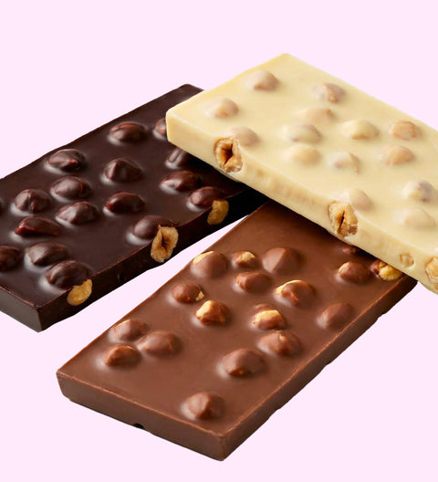 Three chocolate bars with hazelnuts on a light purple background