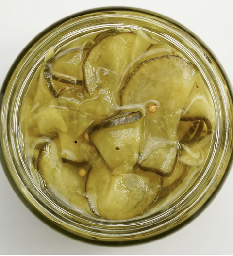 Top view of a jar with pickled cucumbers on a white background