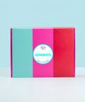 Colorful hamper gift box with a 'Congrats' sticker on a light blue background