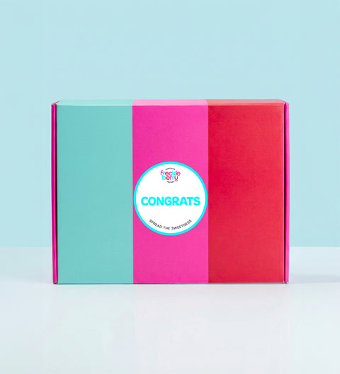Colorful hamper gift box with a 'Congrats' sticker on a light blue background
