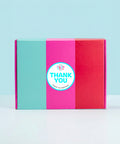 Colorful hamper gift box with a 'Thank You' sticker on a light blue background