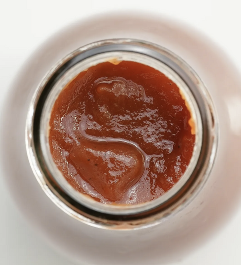 Close-up of a jar of red sauce on a white background