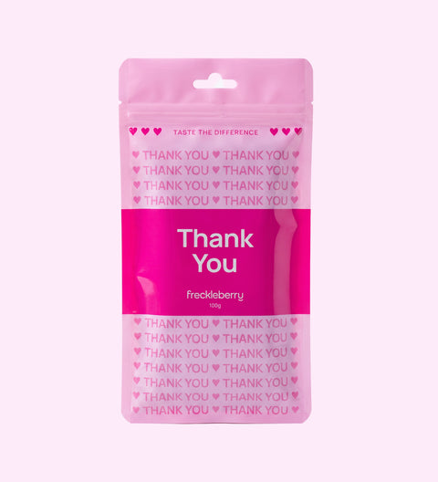 A pink resealable pouch of freckleberry flavored product with 'Thank You' printed prominently on the front, set against a solid pale pink background.