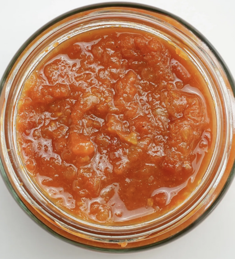 Jar of red tomato relsih on a white background